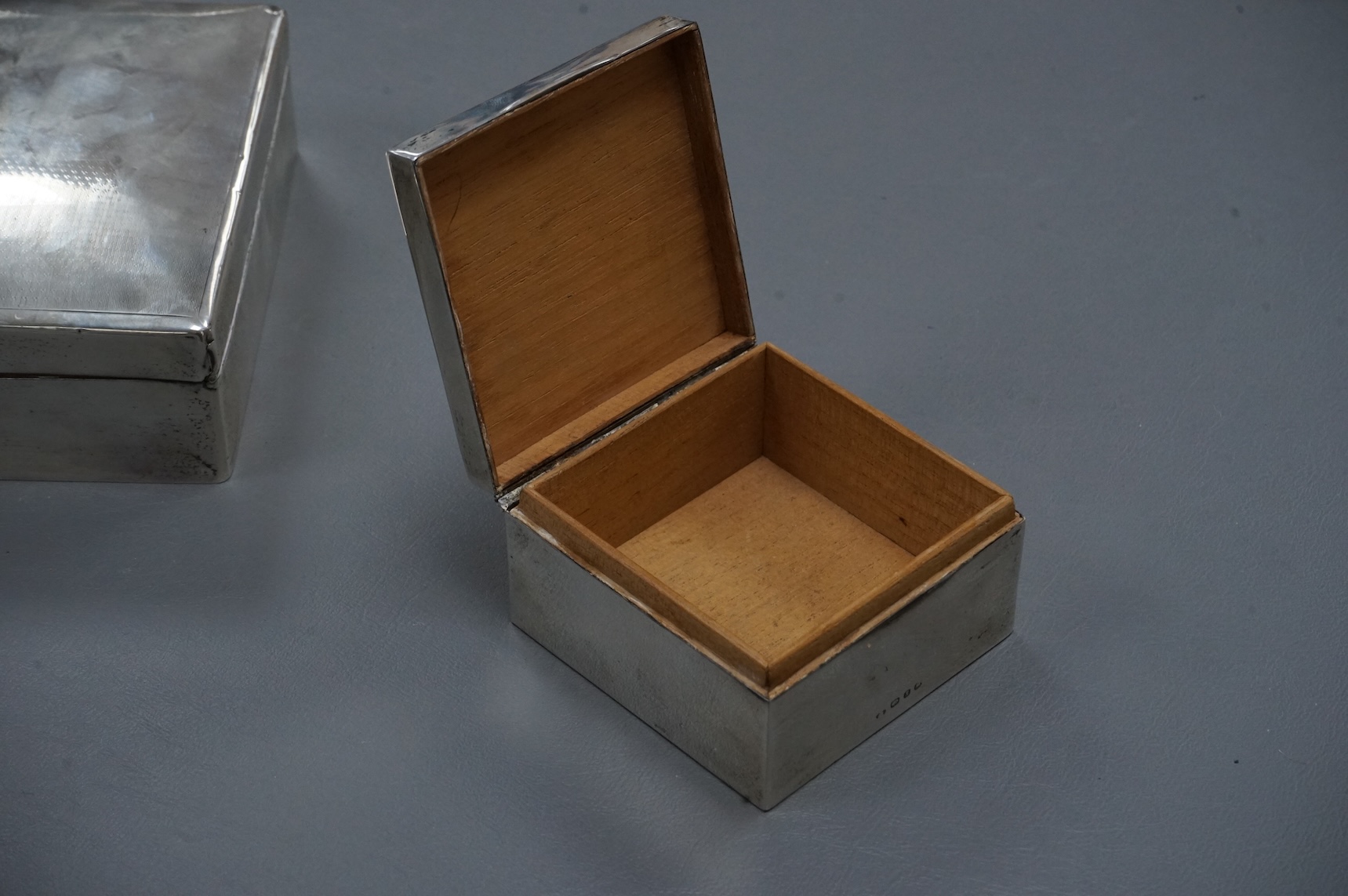 A George V silver mounted rectangular cigarette box, London, 1924, width 16cm, together with a smaller silver mounted cigarette box and a silver cigarette case.